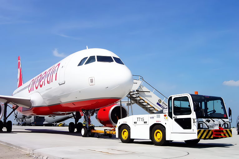Aircraft ground support equipment in operation – tow tractor and passenger steps servicing a commercial airplane on the tarmac